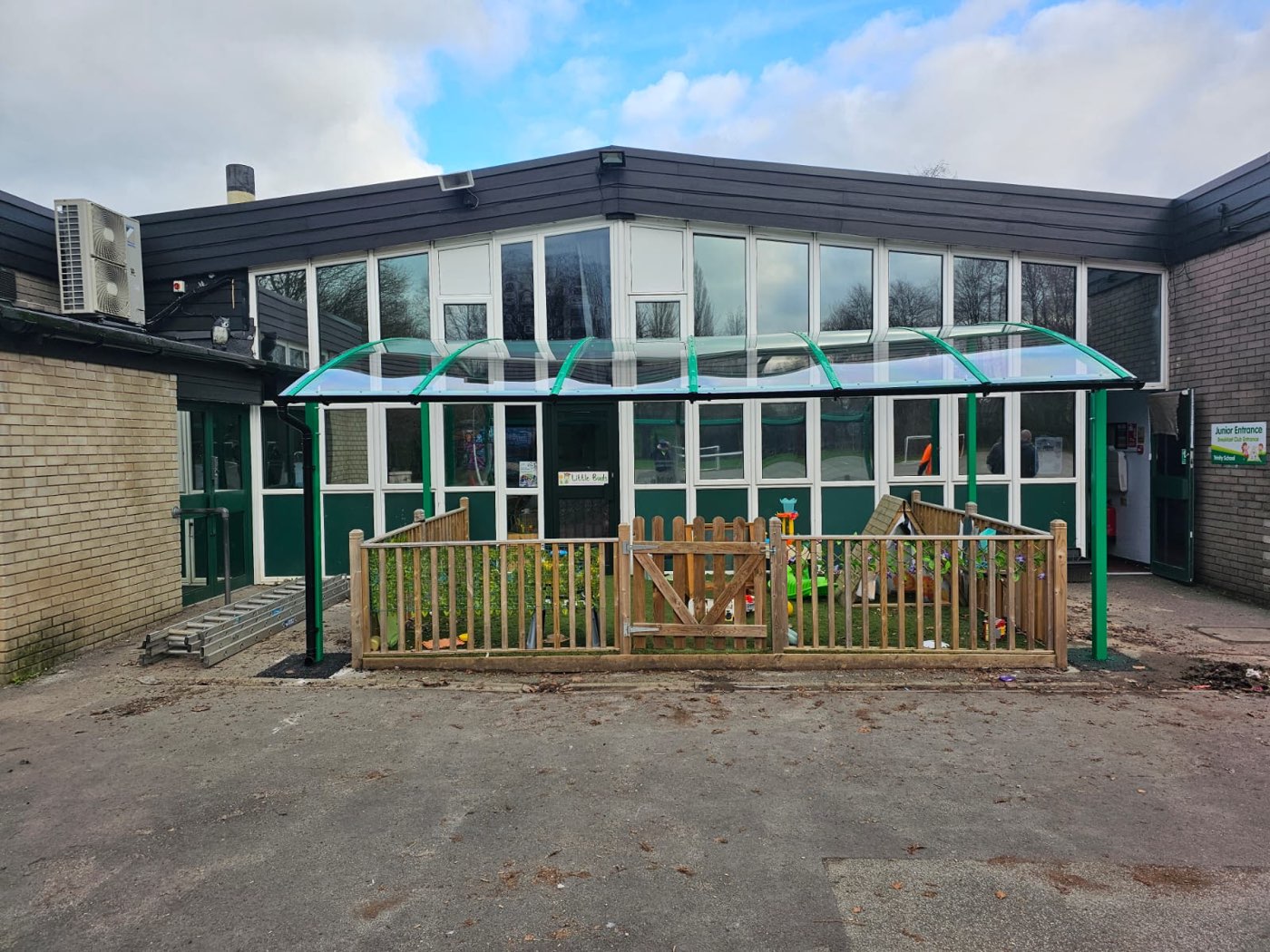 A green steel playground canopy installed at a school
